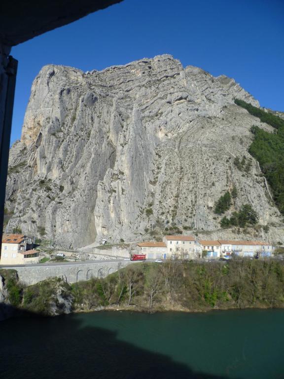 Une montagne à côté d'une masse d'eau et d'une route dans l'établissement Une vue sur la Baume, à Sisteron