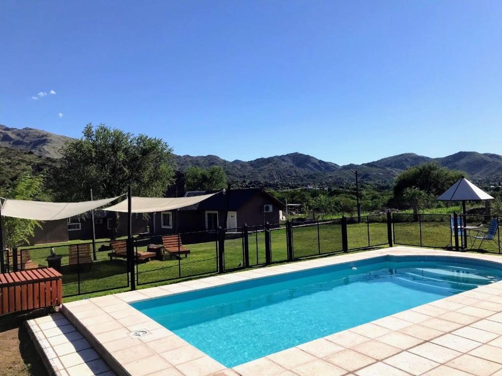 a swimming pool with a fence and a house at Cabañas la Delfina in Potrero de los Funes