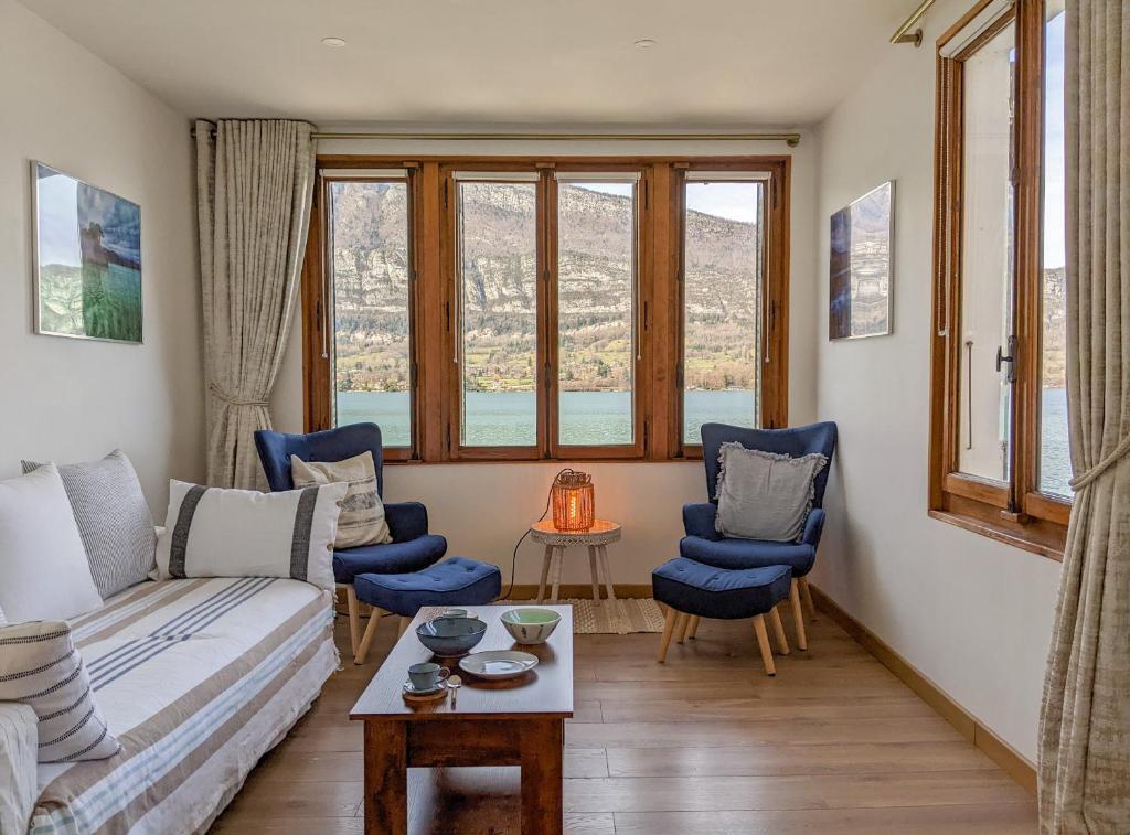 a living room with a couch and chairs and windows at Reflet Bleu du Lac d'Annecy 3 étoiles - Face au lac, Parking gratuit, Paddle board in Doussard
