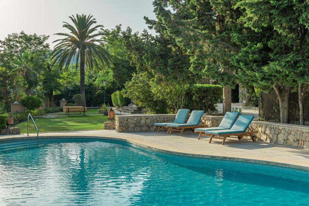 a swimming pool with two blue lounge chairs next to it at Rondaia in Esporles