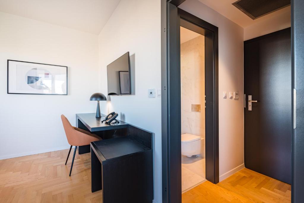 a bedroom with a desk and a room with a toilet at Miramare Hotel in Zadar