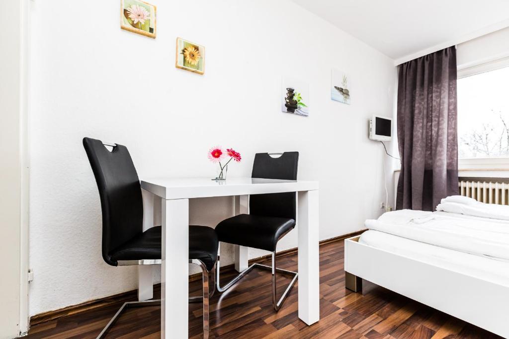 Habitación con mesa blanca y sillas negras. en Easy Apartments Work and Stay Cologne, en Colonia