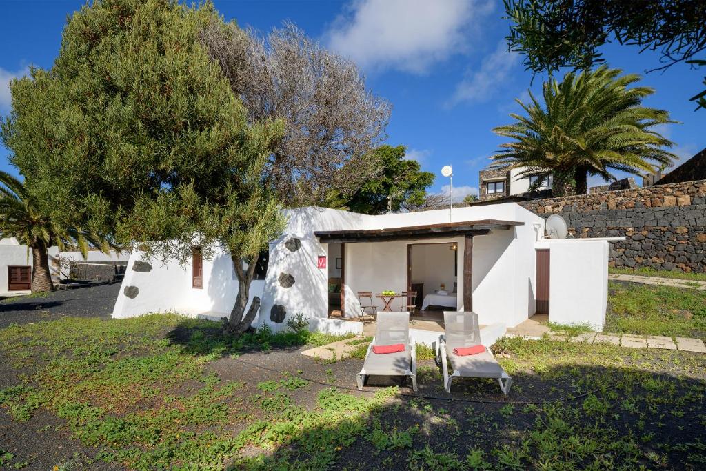 a small house with two chairs and a tree at Casa Los Divisos in Teguise