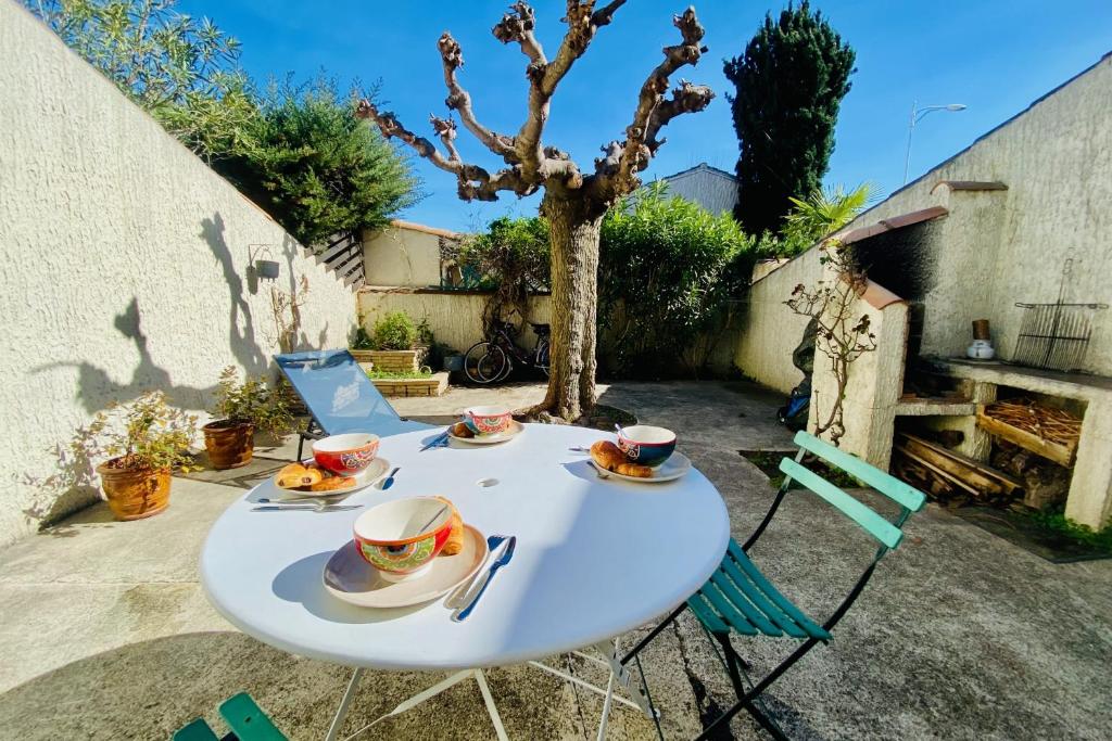 Biały stół z kubkami i spodkami na nim w obiekcie La Maison des Sauges - Village house with garden 500m from the beach w mieście Le Grau-du-Roi
