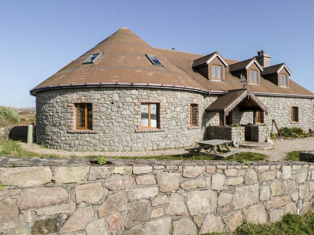 un bâtiment en pierre avec un toit au-dessus d'un mur en pierre dans l'établissement Baile Na Cille, à Knock