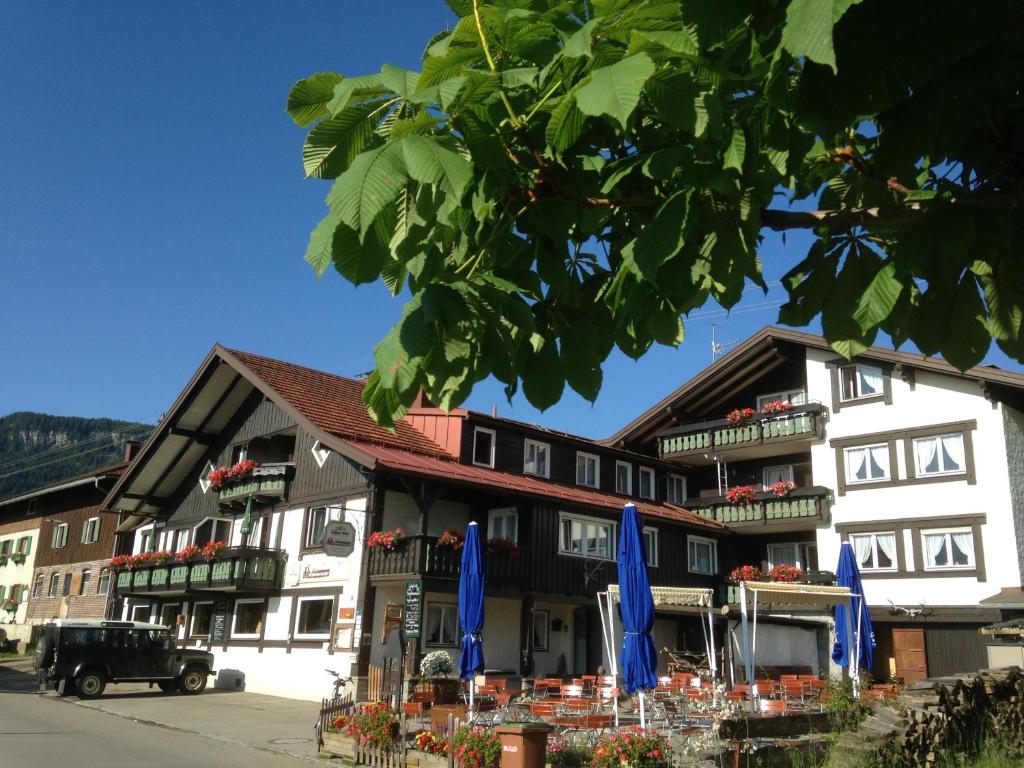 un bâtiment avec des parasols bleus devant lui dans l'établissement Bergbauernwirt im Landhaus Bolgental, à Bolsterlang