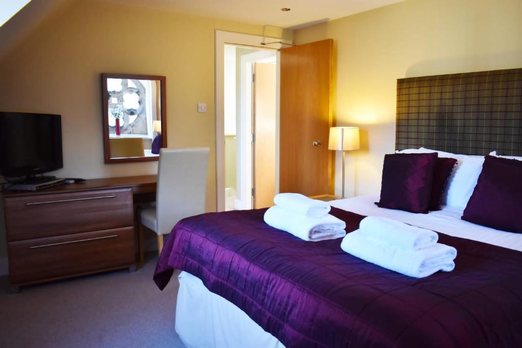 a hotel room with two beds with towels on them at The Ross 2 bedroom apartment in historic Abbey in Fort Augustus