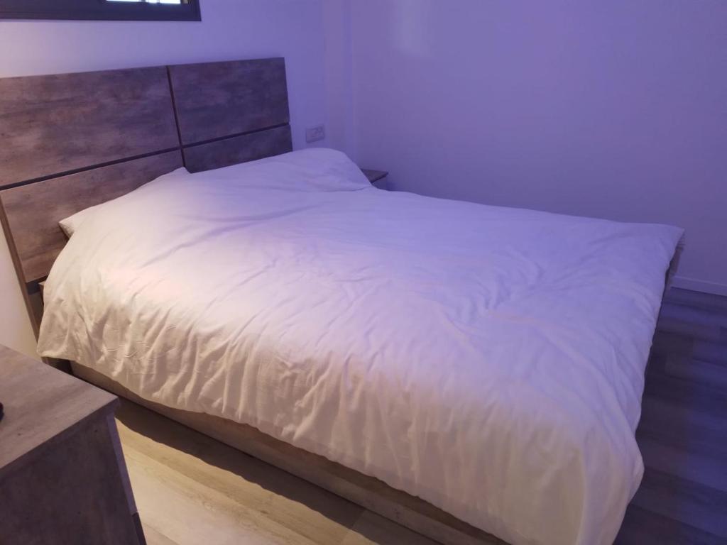 a bedroom with a white bed with a wooden headboard at Puy Rambam's apartment Tiberias in Tiberias