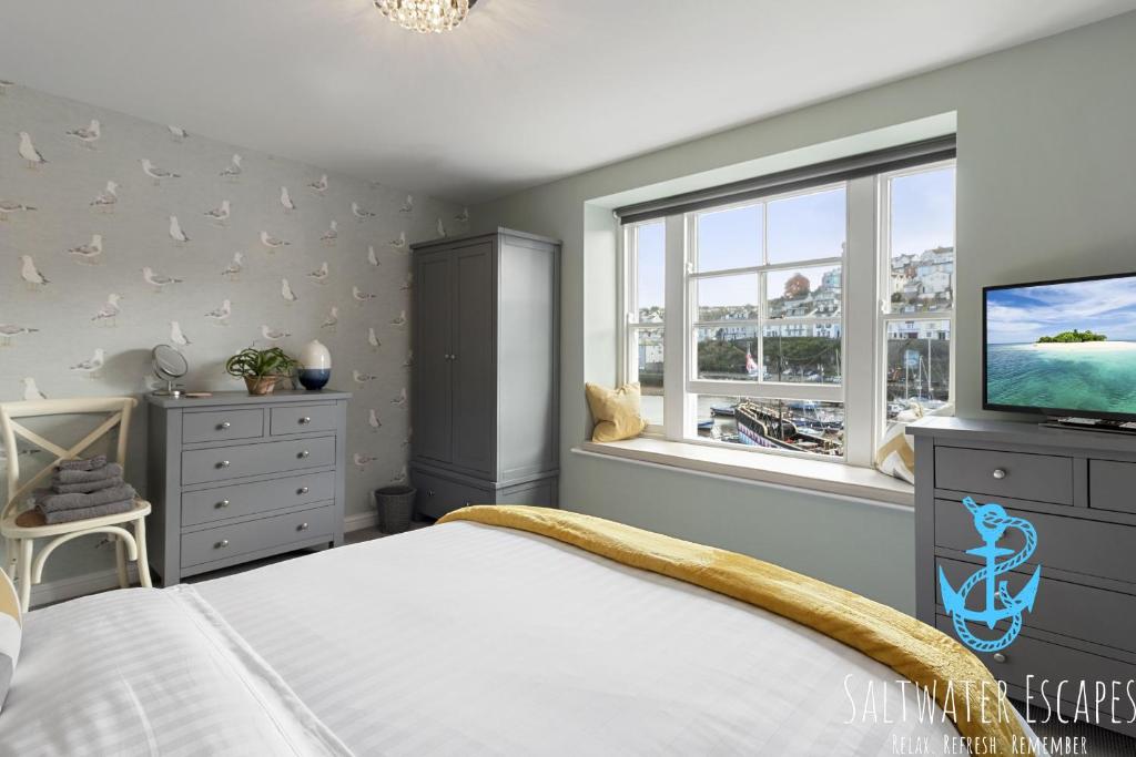 a bedroom with a bed and a tv and a window at La Petite Maison Apartments in Brixham