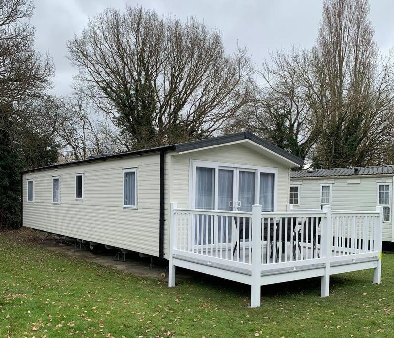 uma casa móvel branca com um alpendre e árvores em Kellysholidayhomes NEW Malton 3 bedroom Caravan em Weeley