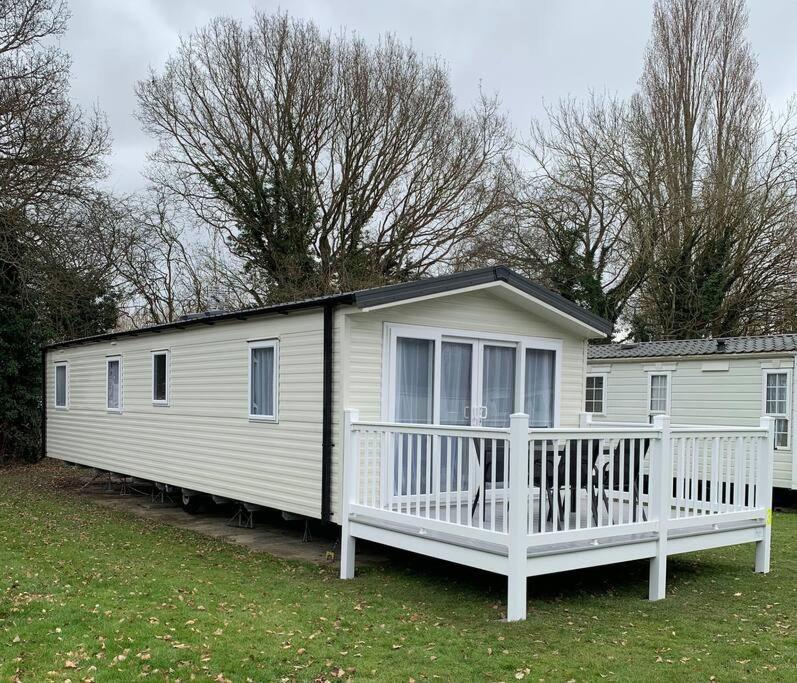 a white mobile home with a porch and trees at Kellysholidayhomes NEW Malton 3 bedroom Caravan in Weeley