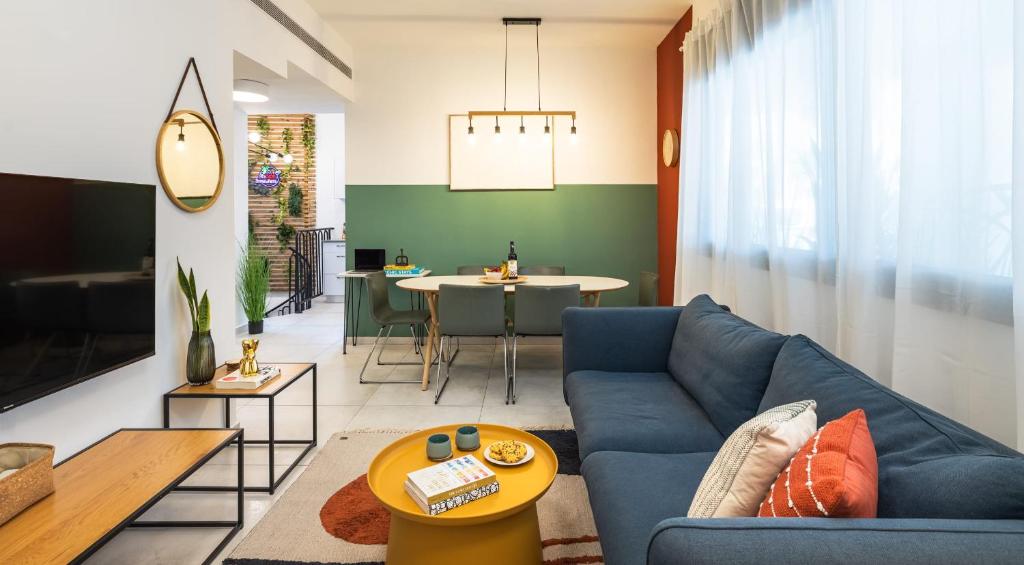 sala de estar con sofá azul y mesa en Beach & Market Designed Duplex en Tel Aviv