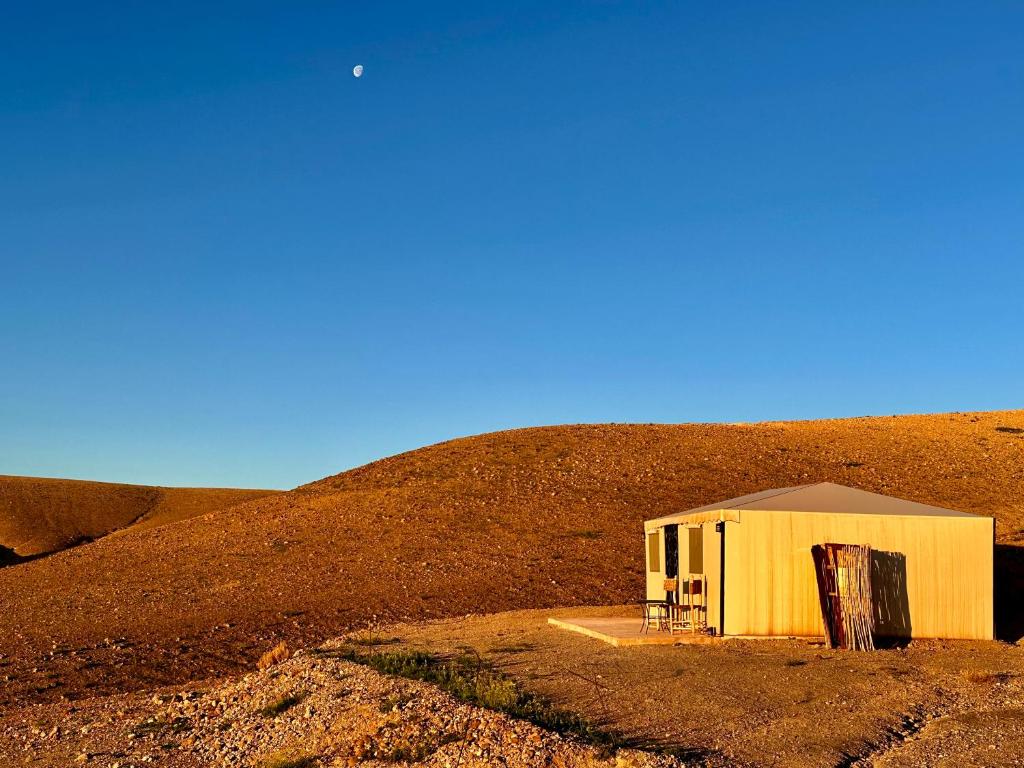 a small yellow building in the middle of a hill at Camp Cameleon in Marrakech