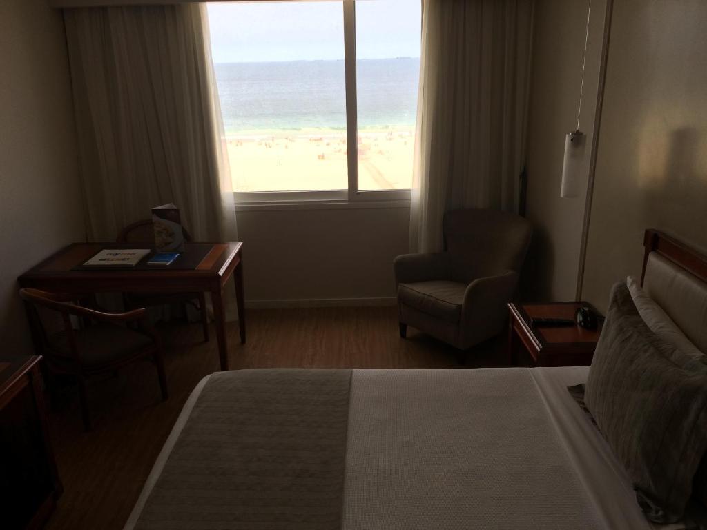 a hotel room with a bed and a desk and a window at Olinda Rio Hotel in Rio de Janeiro