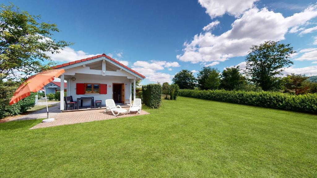 una pequeña casa blanca con un paraguas en un patio en Ferienblockhaus 4, en Löwenstein