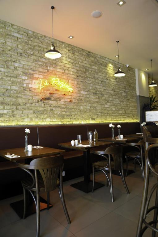 a restaurant with wooden tables and a brick wall at Kings Cross Inn Hotel in London