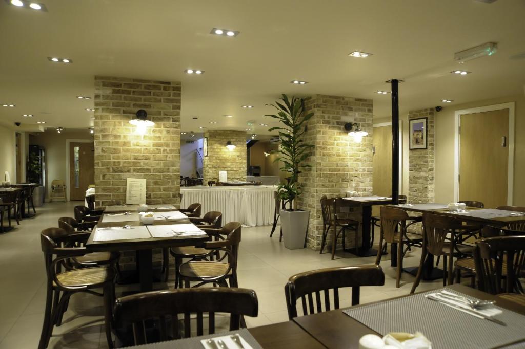a dining room with tables and chairs in a restaurant at Kings Cross Inn Hotel in London