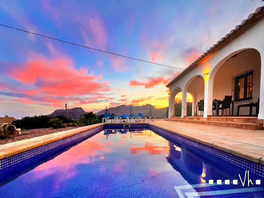 a swimming pool in front of a house with a sunset at VH CostaBlanca - OSALVA in Benissa