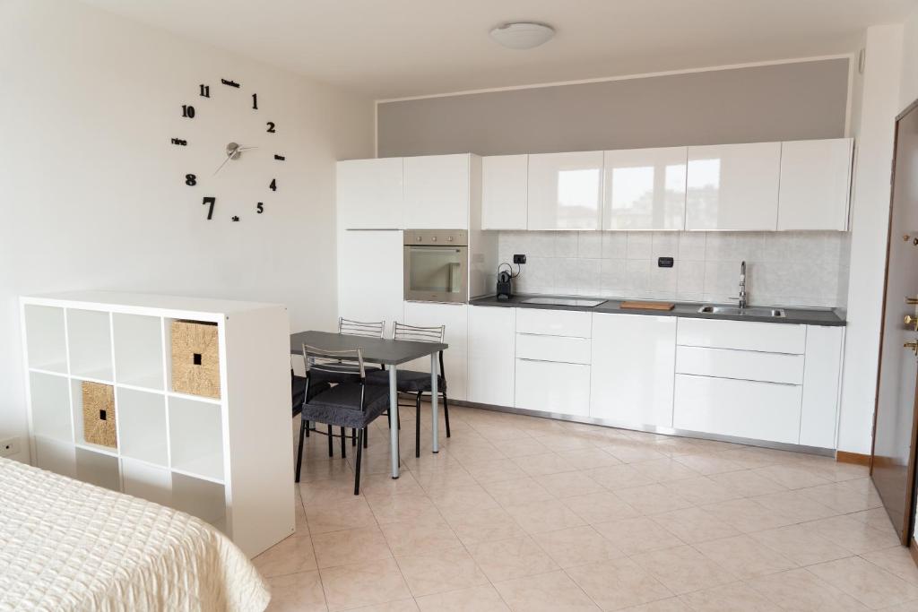 a kitchen with white cabinets and a table and chairs at Parcheggio Privato - Appartamento a Milano in Corsico