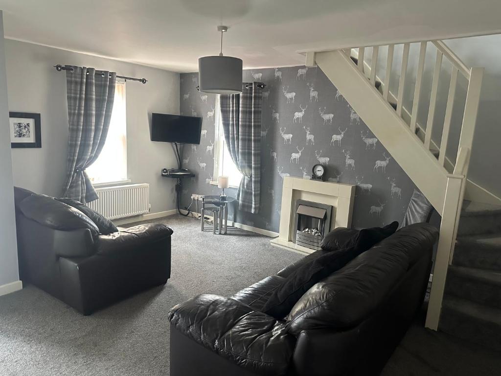 a living room with a couch and a stair case at 3 Dialknowe Holiday Cottage - Wanlockhead - 3 Bedrooms in Wanlockhead