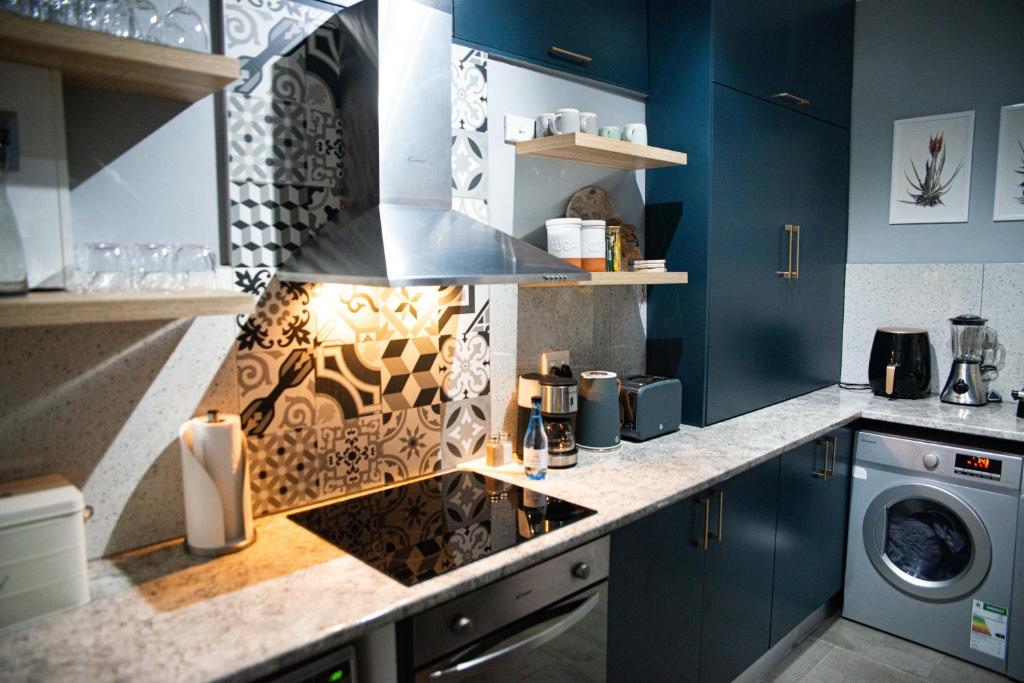 a kitchen with blue cabinets and a stove top oven at Mdumela Stays 2 Bedroom Modern City Apartment in Pietermaritzburg