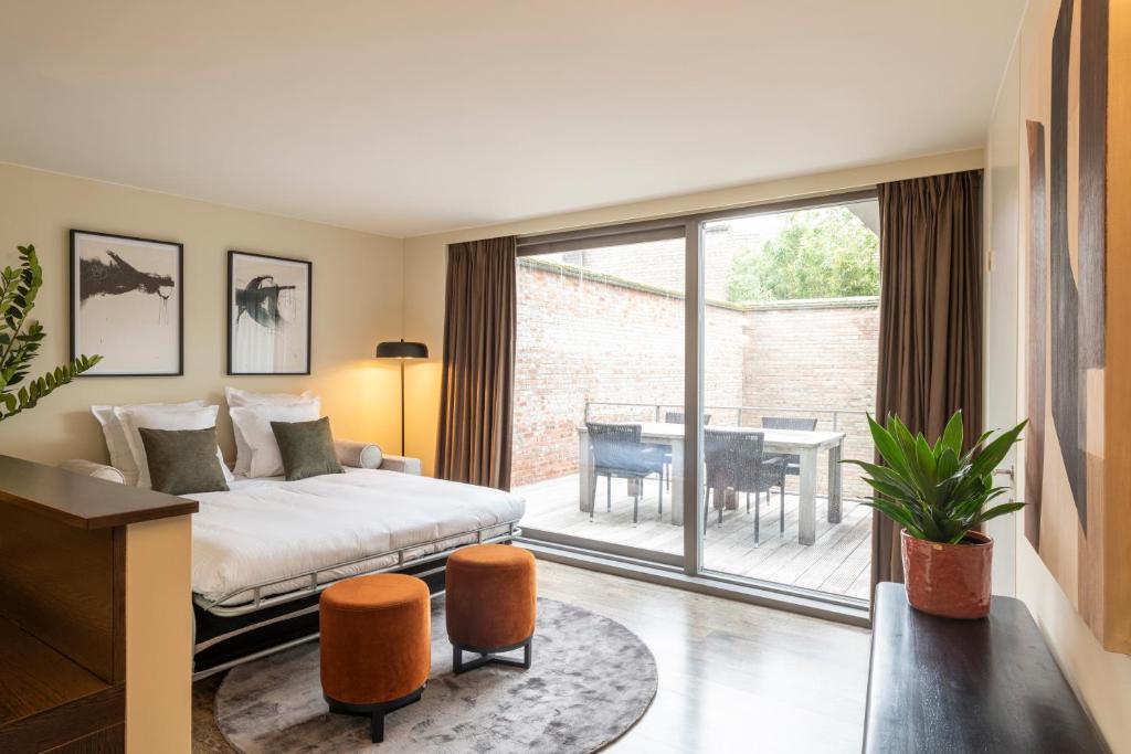 a bedroom with a bed and a balcony with a table at Dukes' Apartments Grand Place in Bruges