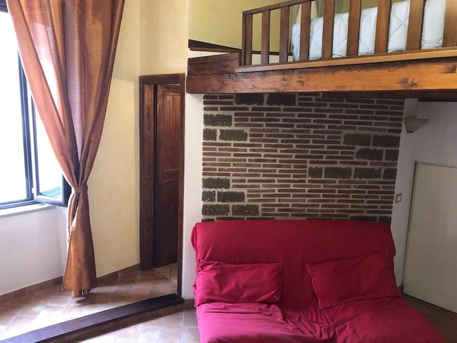 un sofá rojo en una habitación con una pared de ladrillo en Grazioso appartamento in centro storico, en Terracina