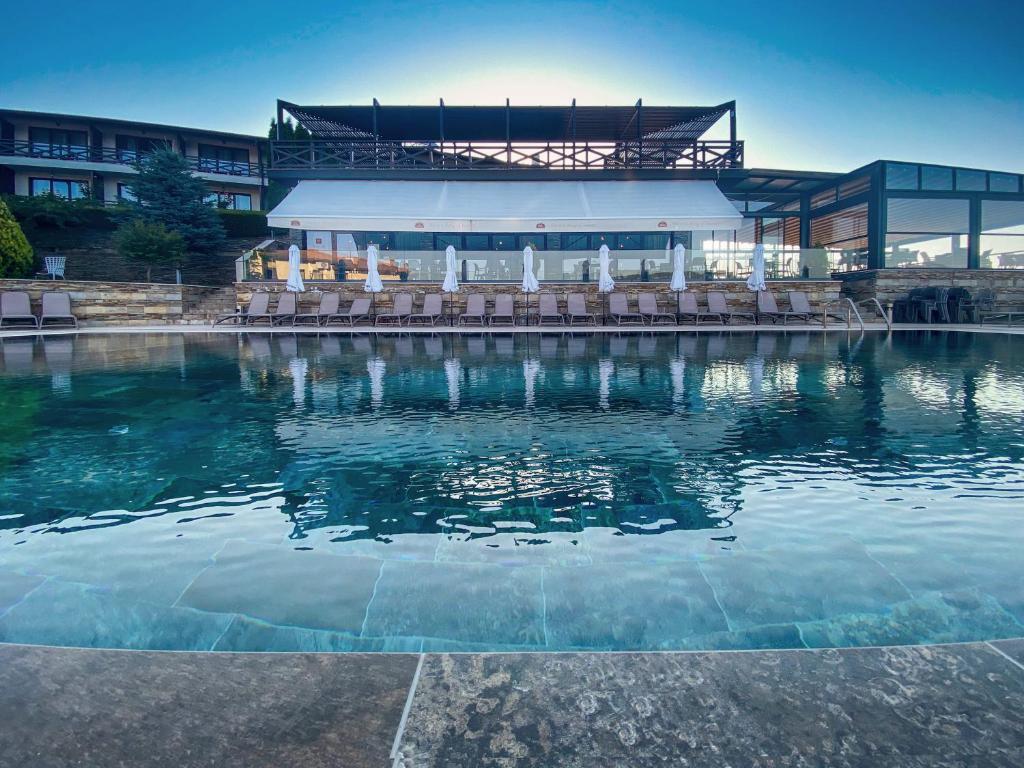 een zwembad met stoelen en een gebouw bij Rocca Resort in Glavatartsi