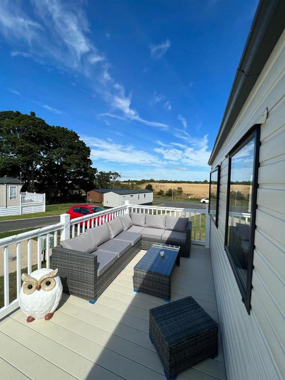 a deck with a couch and chairs on a balcony at Lotus Lodge Northumberland in Felton