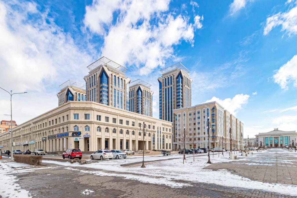 een groep hoge gebouwen op een besneeuwde straat bij Жк Millennium Park,на Главной площади страны. in Astana