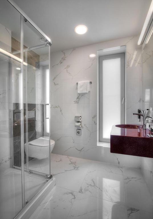 a bathroom with a glass shower and a sink at Hotel Essence in Prague