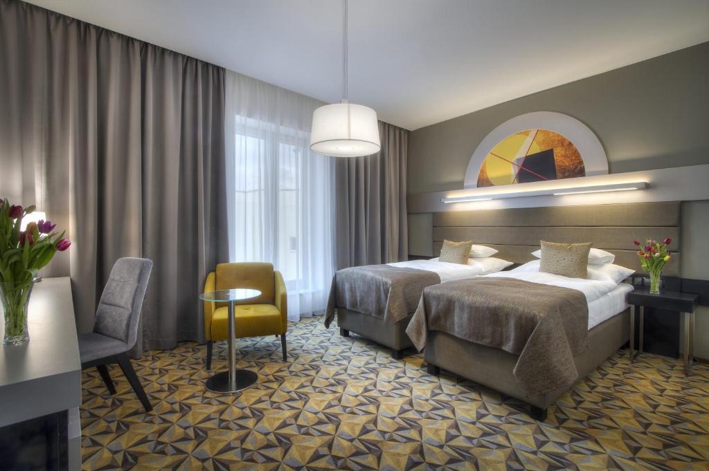 a hotel room with two beds and a chair at Hotel Essence in Prague