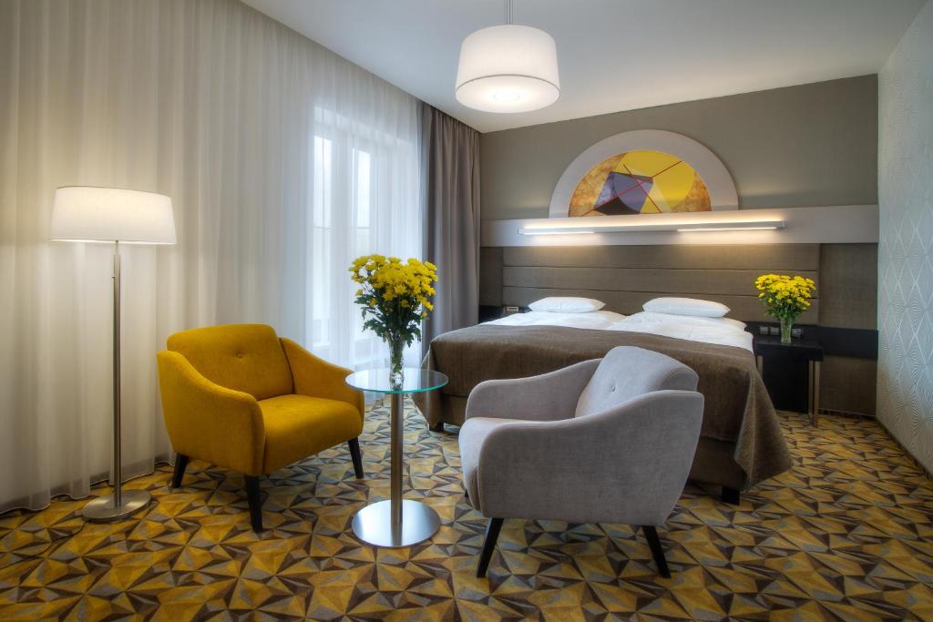 a hotel room with two beds and two chairs at Hotel Essence in Prague