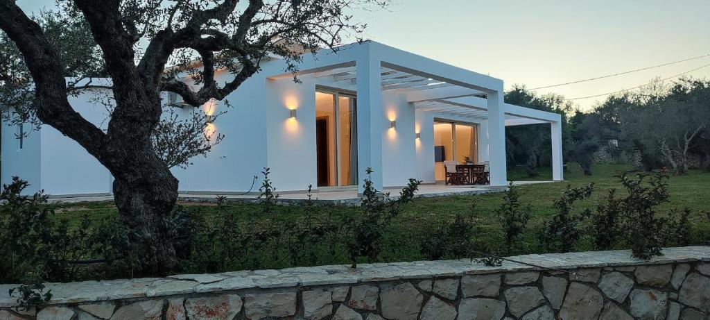 una casa blanca con un árbol y una pared de piedra en Villa Mavra en Plános