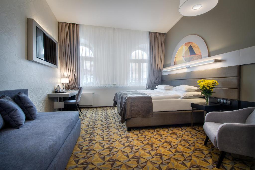 プラハにあるHotel Essenceのベッドとソファ付きのホテルルーム