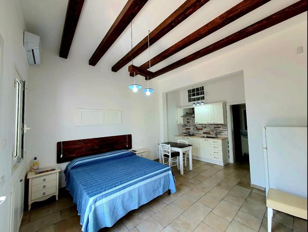 a bedroom with a blue bed and a kitchen at Lu Salentu Chalet Beach in Marina di Mancaversa