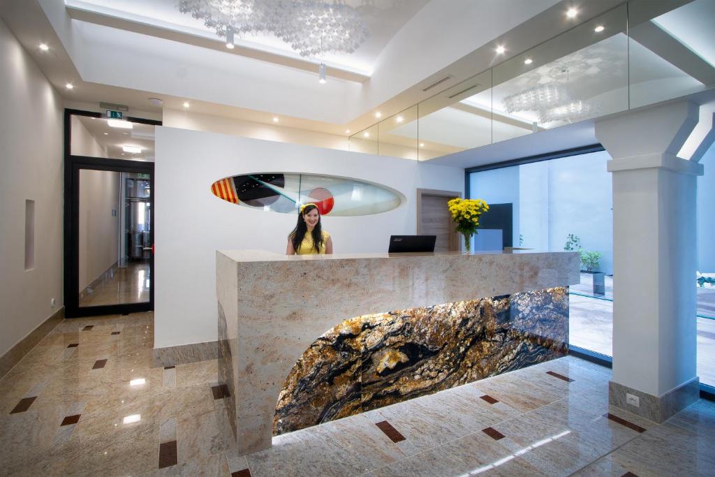 a woman standing at a reception desk in a lobby at Hotel Essence in Prague