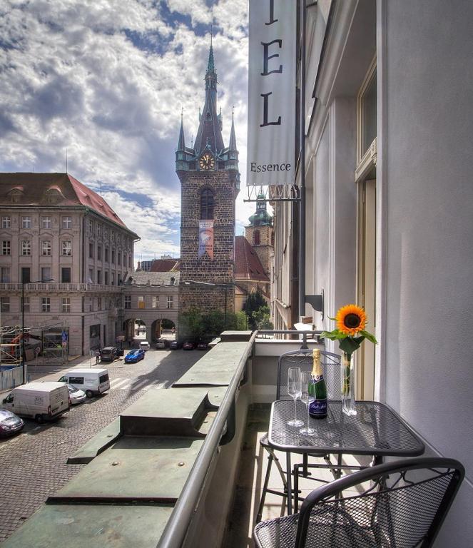 a balcony with tables and chairs and a clock tower at Hotel Essence in Prague