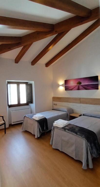 two beds in a room with wooden ceilings at Hostal A Cantina de Renche in Renche
