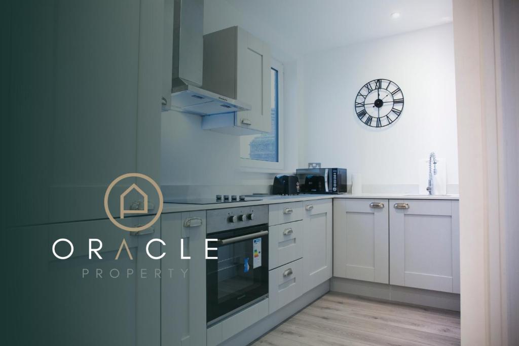 a kitchen with white cabinets and a clock on the wall at Bishops Lynn House Apartments - Town Centre in Kings Lynn