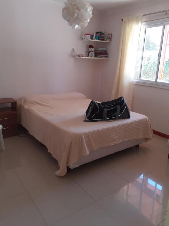 a bedroom with a bed with a black bag on it at Mi lugar de encuentro. in General Roca