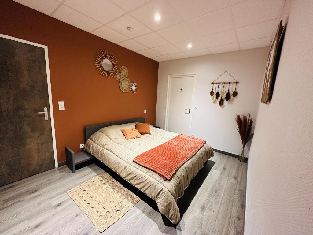 a bedroom with a large bed with an orange blanket at L'Entrepotes in Rethel