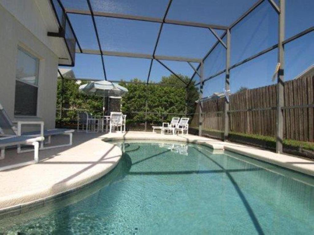 a swimming pool with two chairs and an umbrella at Turkey Oak Villa IR021 in Kissimmee