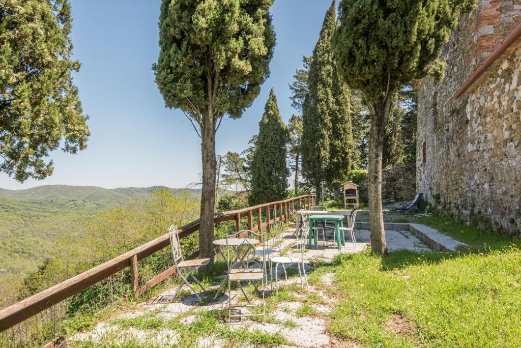 una mesa y sillas en un balcón con árboles en Casale Rosennano - Riserva en Rosennano