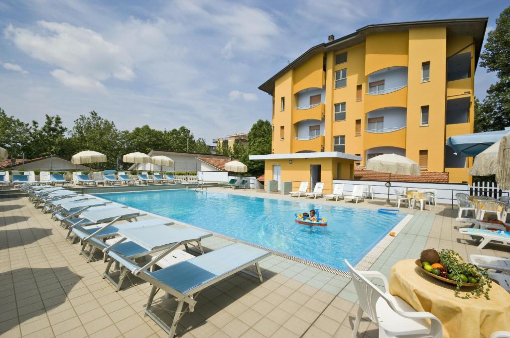 a swimming pool with lounge chairs and a hotel at VMBabyhotel & Residence Parador in Cesenatico