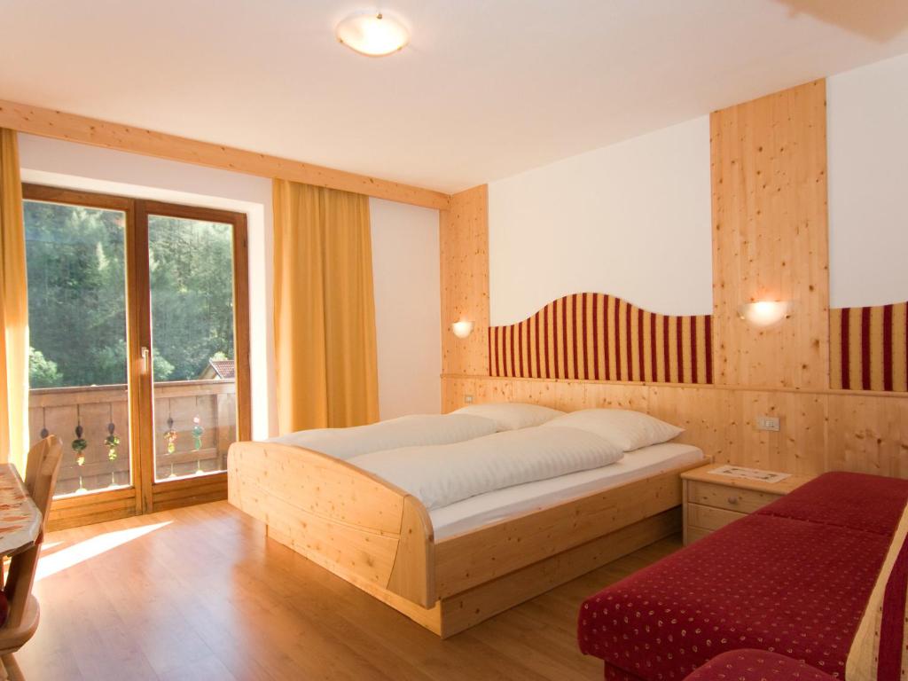 a bedroom with a bed and a large window at Pension & Appartament Anna in Predoi