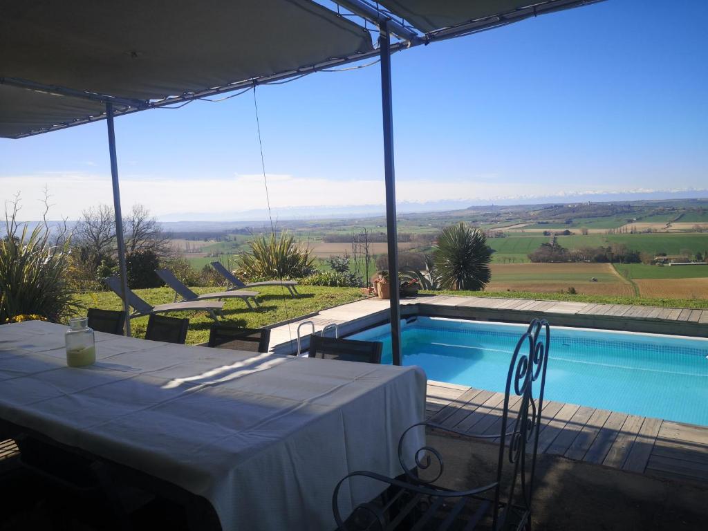 einen Tisch mit einem weißen Tischtuch neben einem Pool in der Unterkunft Villa piscine avec vue exceptionnelle in Puéchoursi