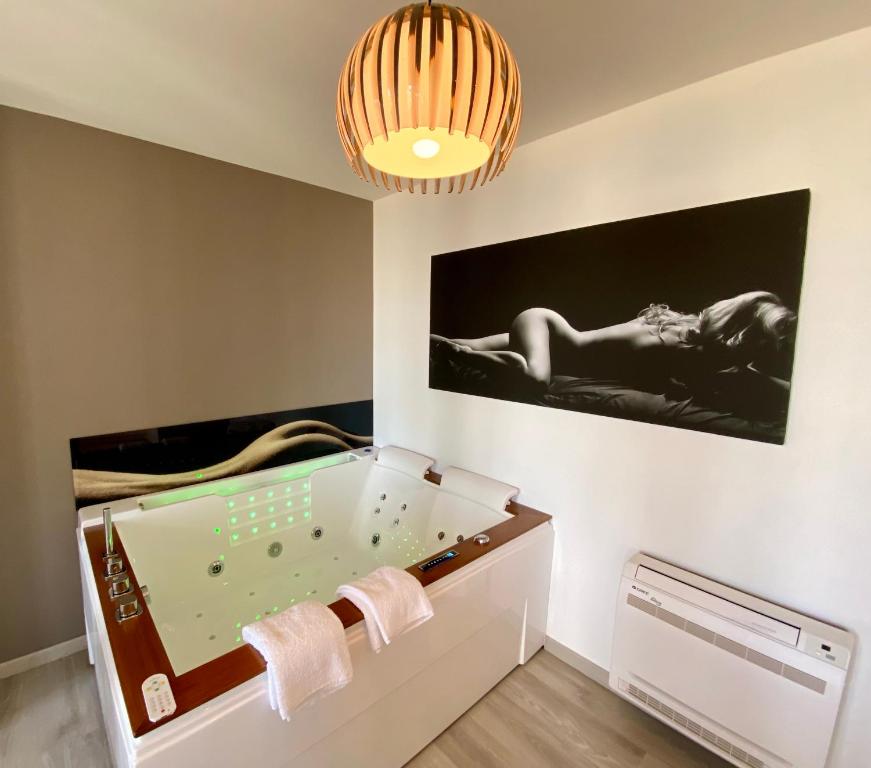 un cuarto de baño con jacuzzi con una foto en la pared en La Vague Tendresse - Vue mer - Jacuzzi & Sauna, en Le Tréport