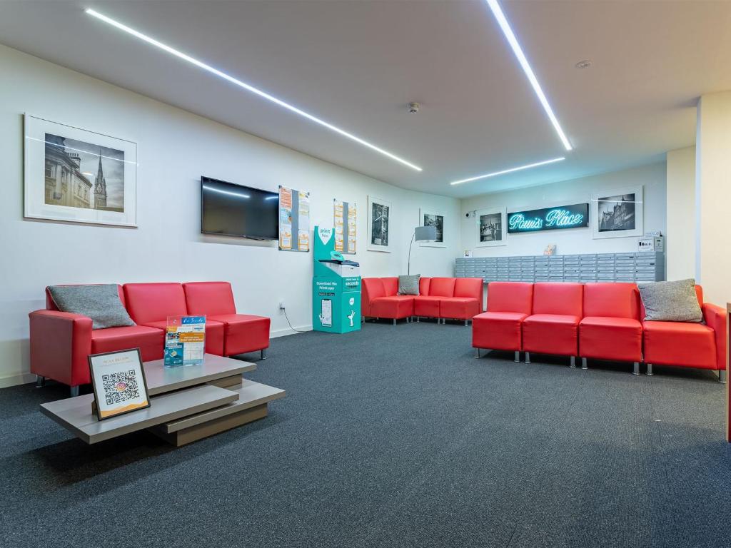 uma sala de espera com cadeiras vermelhas e uma televisão de ecrã plano em For Students Only Ensuite Bedrooms at Powis Place minutes away from Aberdeen City Centre em Aberdeen