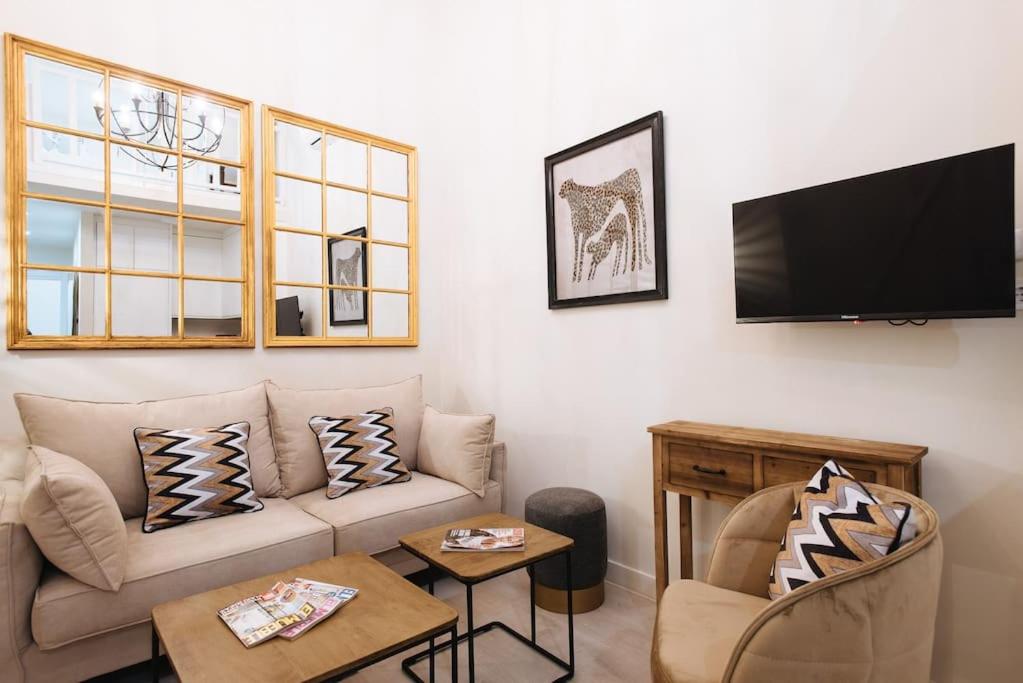 ein Wohnzimmer mit einem Sofa und einem Flachbild-TV in der Unterkunft Elegante y céntrico apartamento in Sevilla